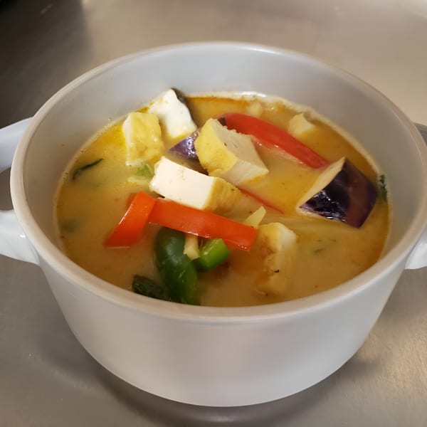 SaiMai Thai Restaurant's yellow curry with tofu, red bell peppers, and eggplant in a white bowl.