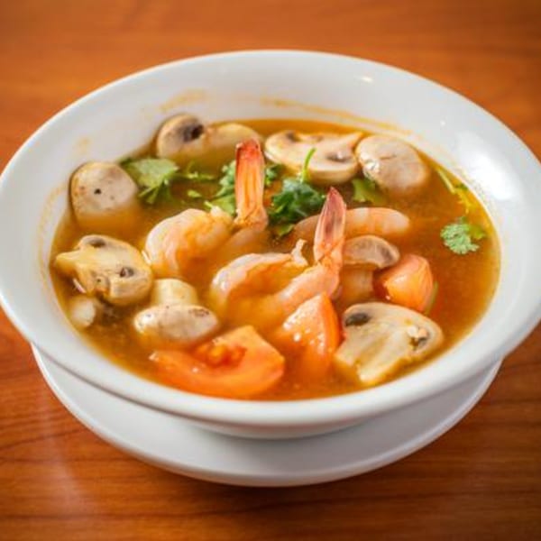 A white bowl of SaiMai Thai Restaurant's Tom Yum soup with shrimp, mushrooms, and tomatoes.