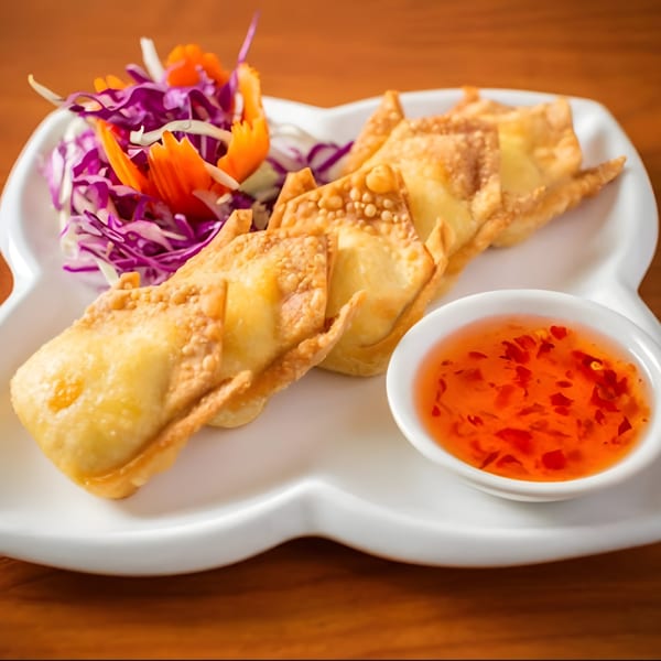 Crispy fried wontons with a side of sweet chili sauce and shredded cabbage salad.